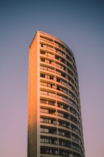 A luxury high-rise building glowing warmly at sunset against a clear sky.