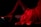 A woman is lying down in a pose with one leg bent and the other extended. She is wearing red fishnet stockings and red high heels, complemented by a red dress. The background is dark, which highlights the vibrant red clothing.