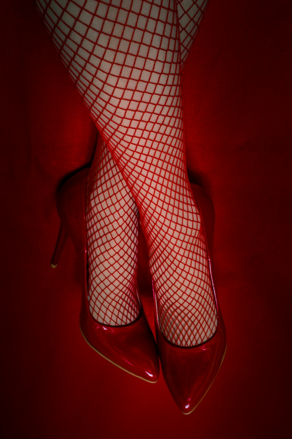 a close up of a person's legs wearing red shoes