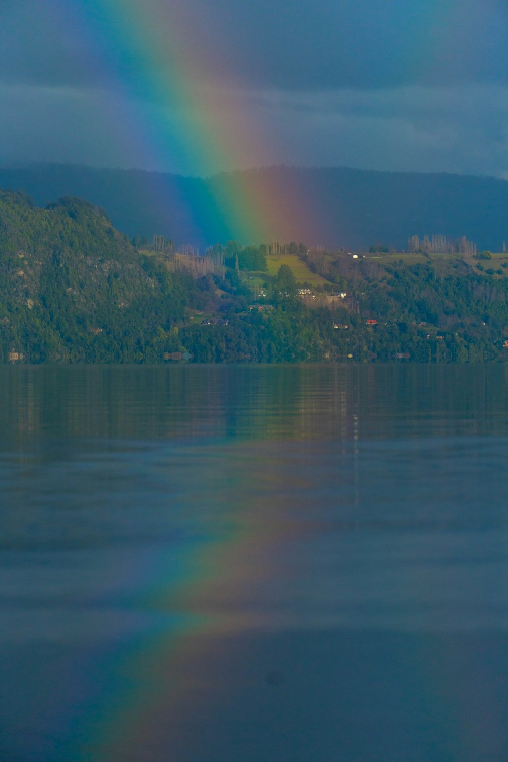 a rainbow shines in the sky over a lake