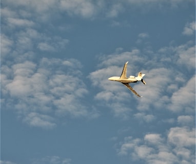 a small plane flying through a cloudy blue sky