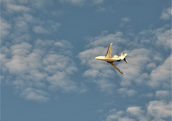 a small plane flying through a cloudy blue sky