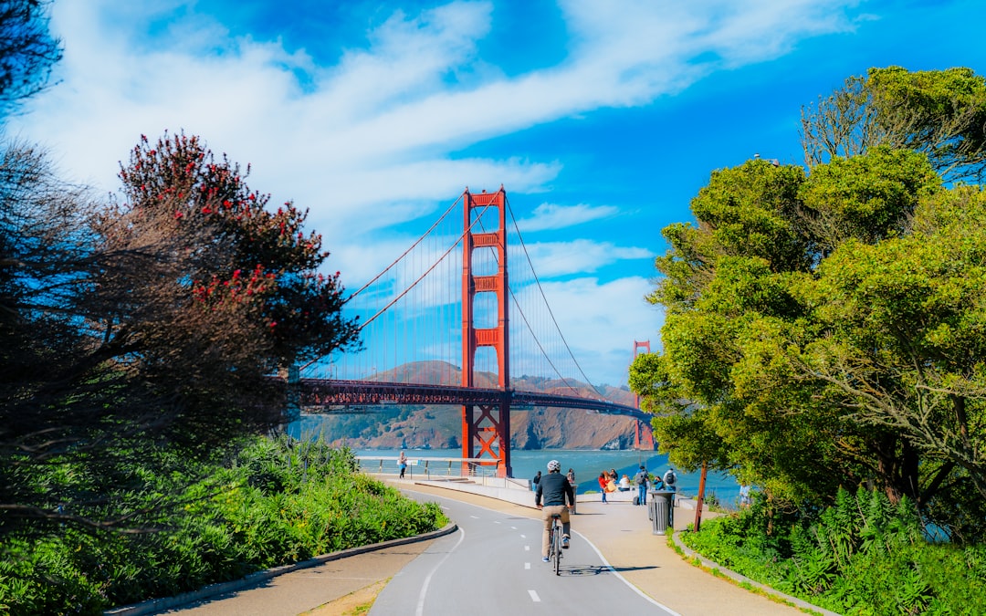 a man riding a bike down a street next to a bridge,