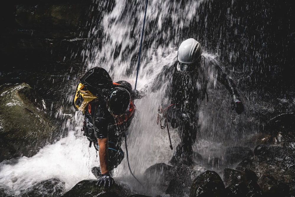 a couple of people standing next to a waterfall