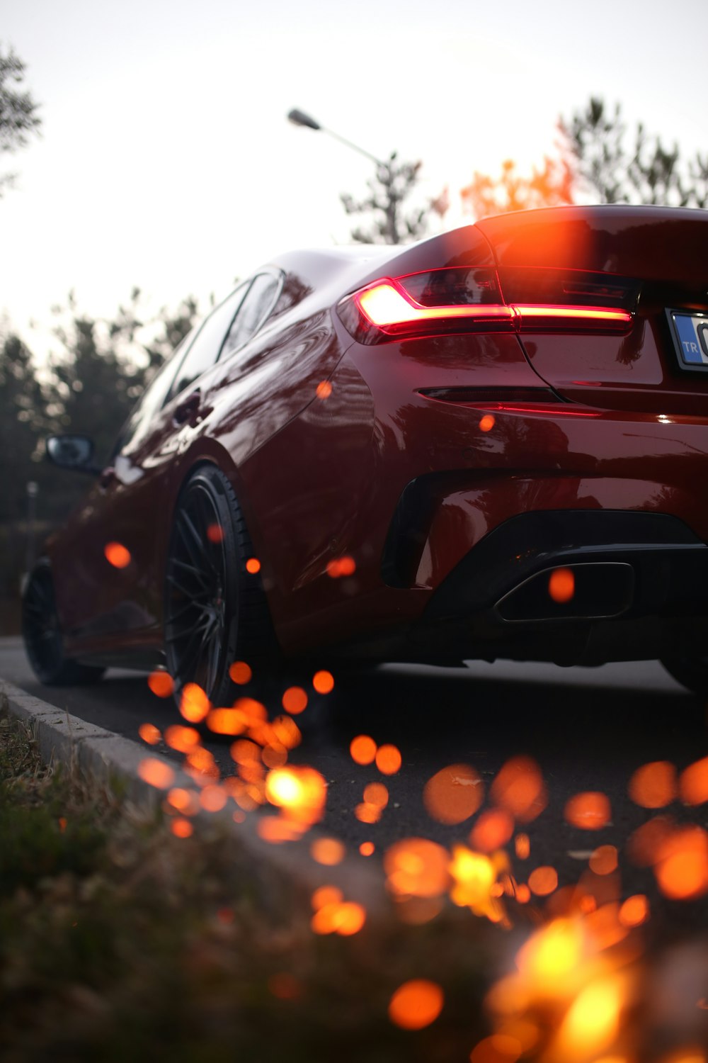 a red car driving down a street next to a forest