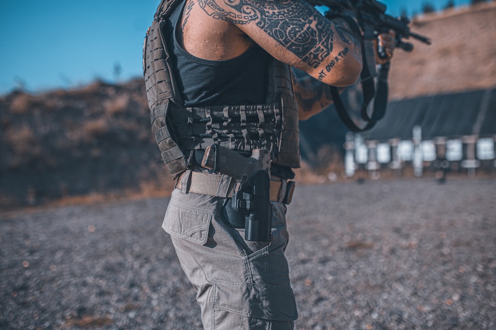 a man with a tattoo on his arm holding a gun