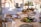 A beautifully set dining table with a three-tiered serving tray filled with a variety of gourmet appetizers. Fresh vegetables, bread, and small dishes of food are arranged artistically. The table is adorned with elegant glassware and an assortment of plates and cutlery, set in a bright, sunlit setting, suggesting a luxurious dining experience.
