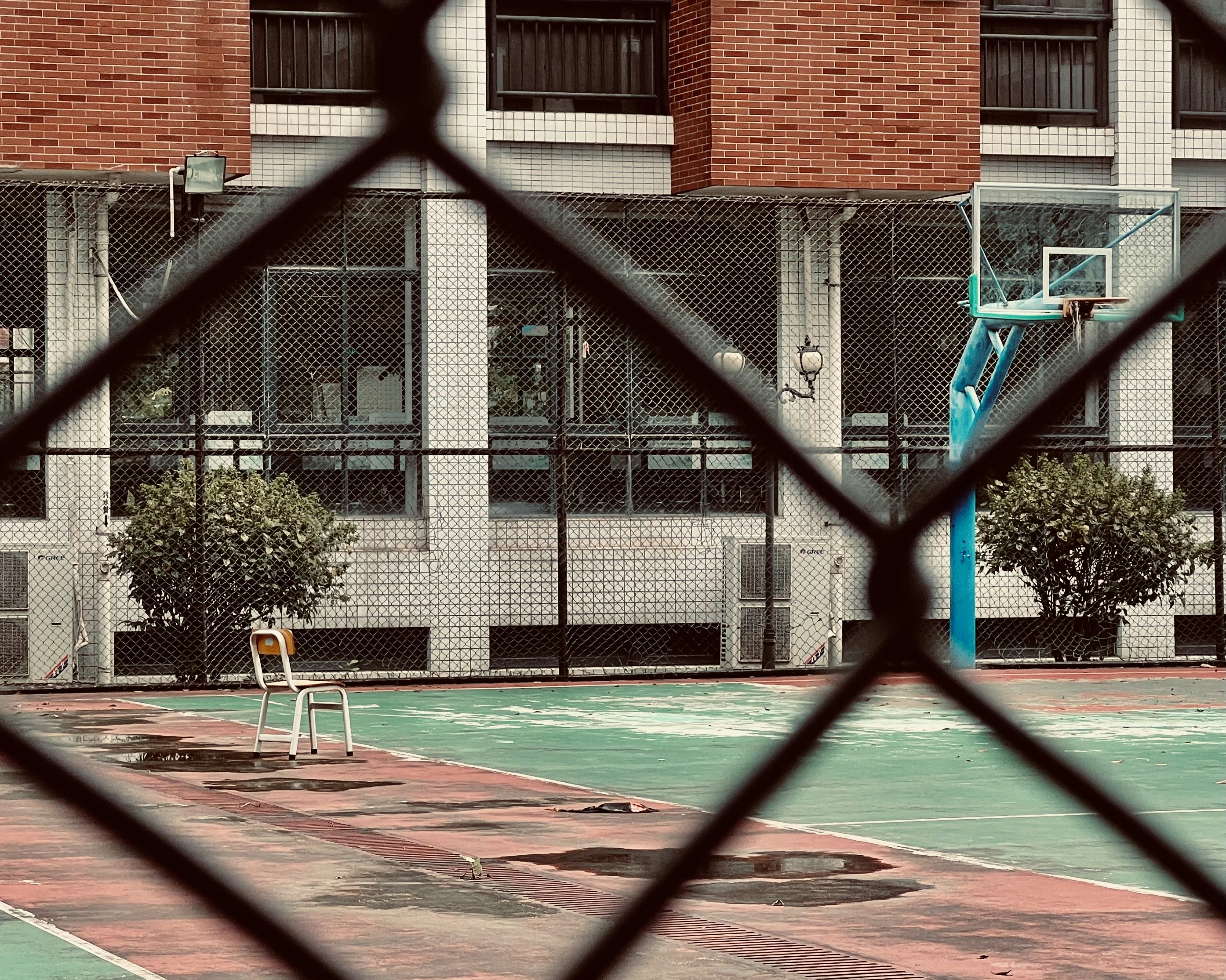 A basketball court behind a fence with a basketball hoop photo Free
