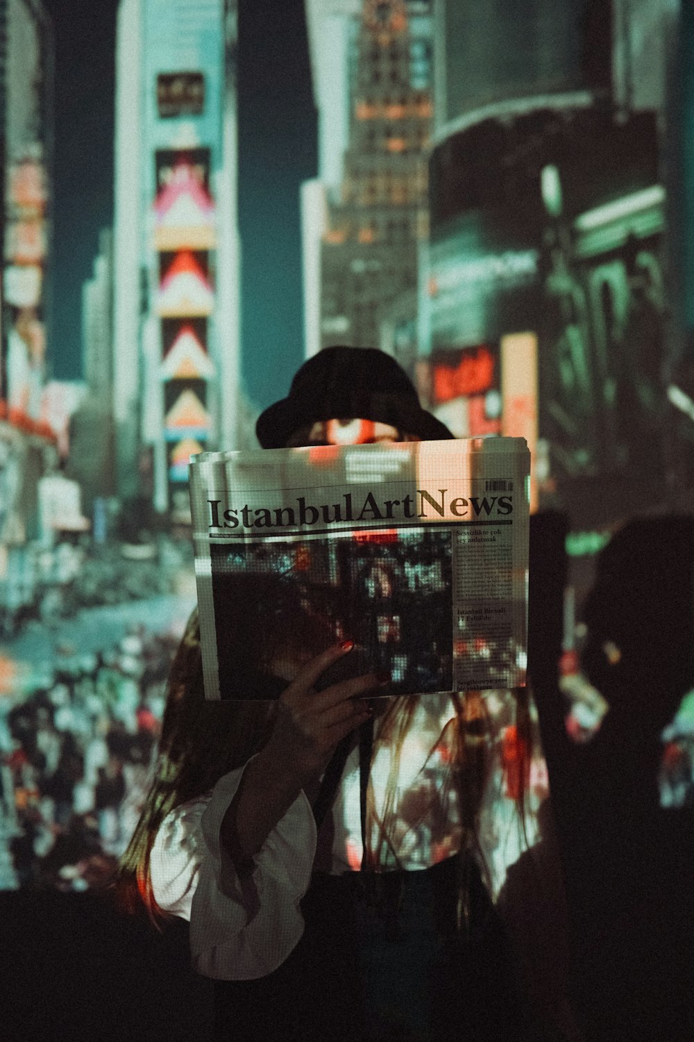 a person holding up a newspaper in front of a cityscape
