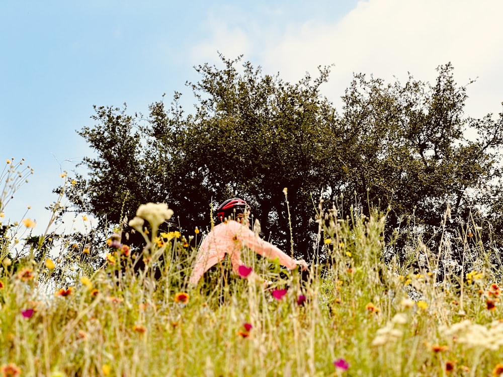 a woman in a field of flowers with trees in the background
