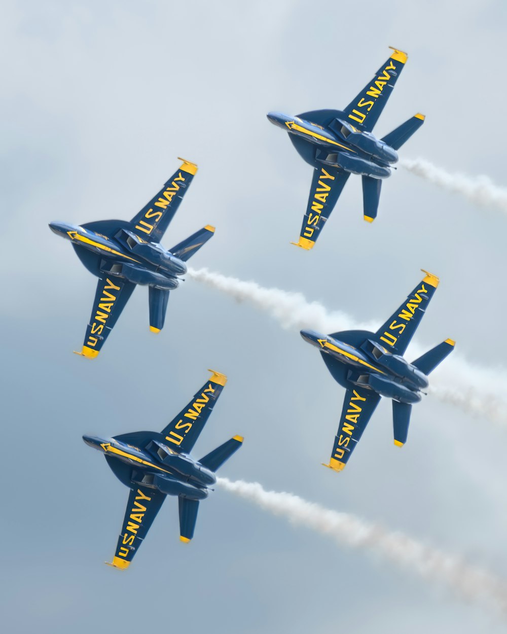 four blue and yellow jets flying in formation