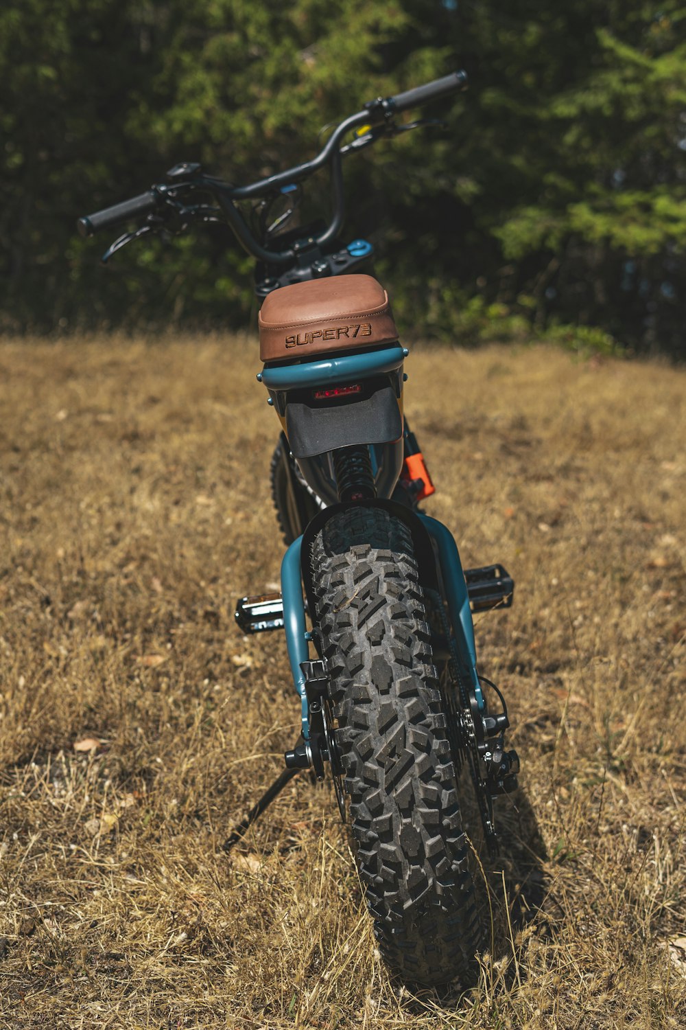 uma motocicleta azul estacionada em um campo com árvores ao fundo