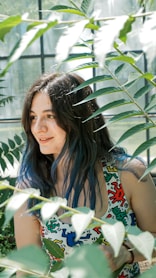 a woman with blue hair sitting in front of a window