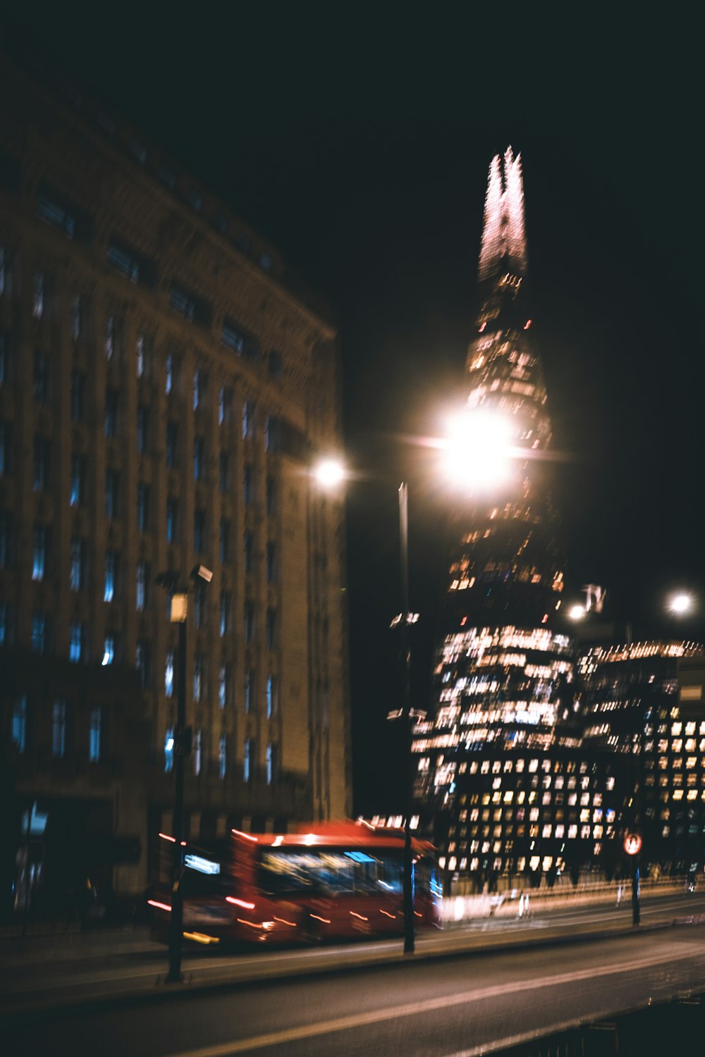 a red bus driving down a street next to tall buildings