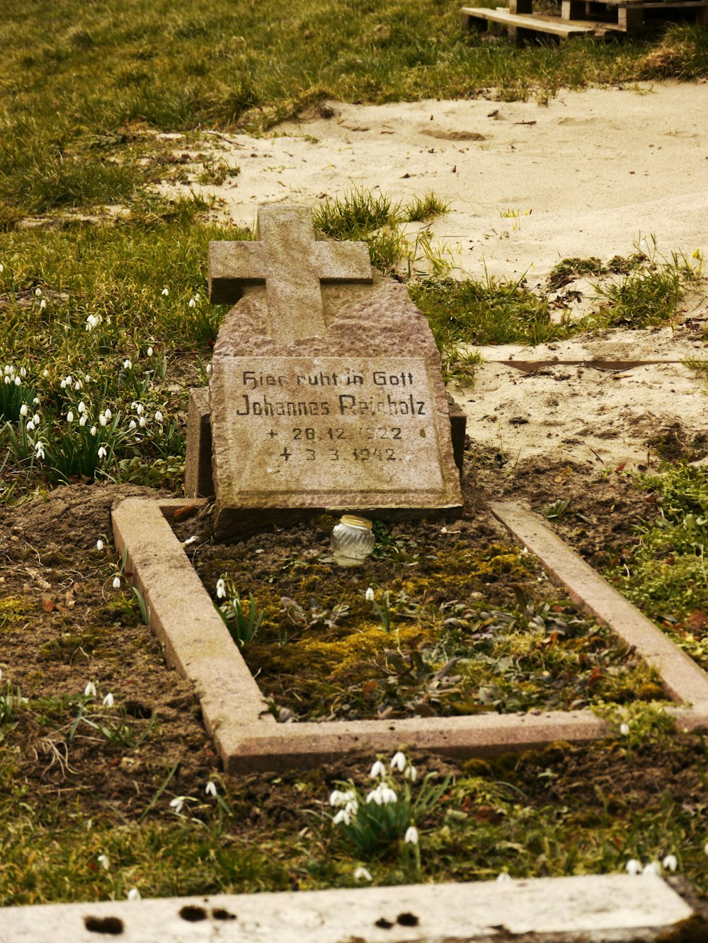a grave in a field with flowers around it