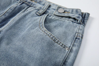 Close-up of classic blue jeans with detailed stitching and a subtle yellow logo patch on the waistband.