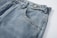 Close-up of a pair of blue denim jeans highlighting the texture and stitching. The focus is on the waistband, button, and a front pocket. The fabric appears sturdy with a slightly faded look.