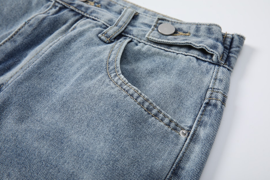 Close-up of a pair of dark indigo jeans with detailed stitching and a leather patch showing the DenimDistrictt logo.