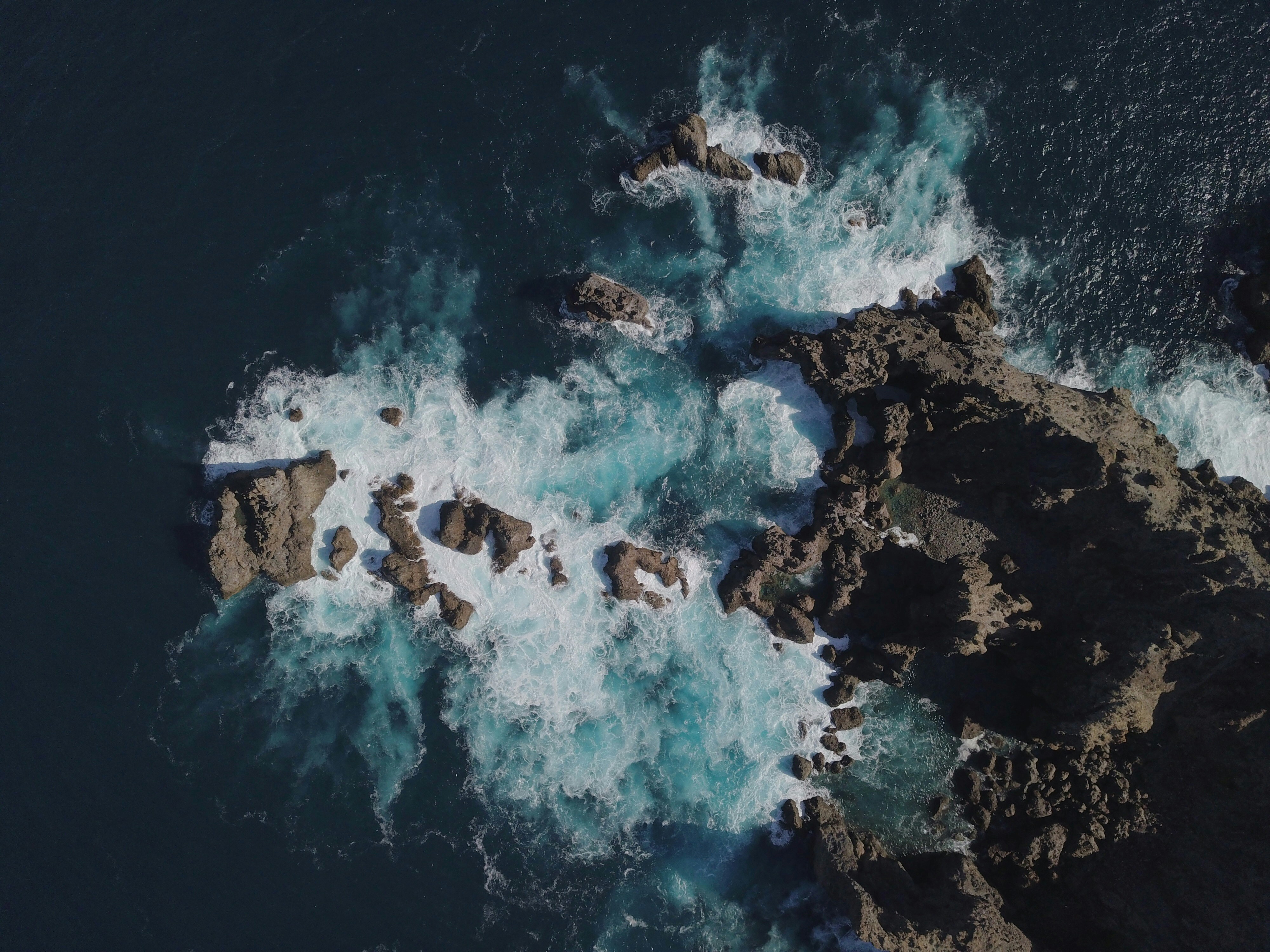 an aerial view of the ocean and rocks