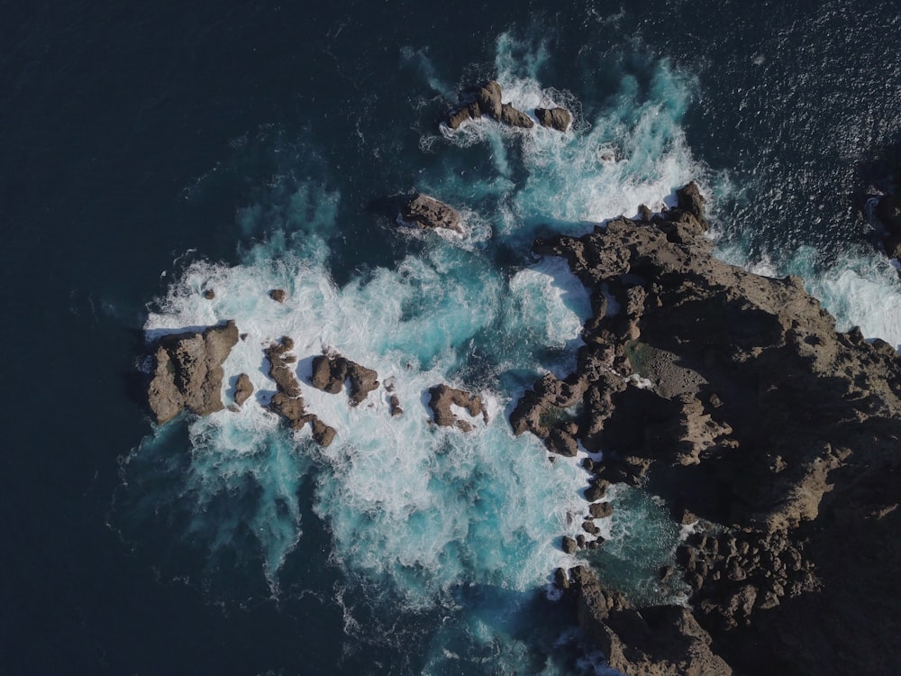 an aerial view of the ocean and rocks