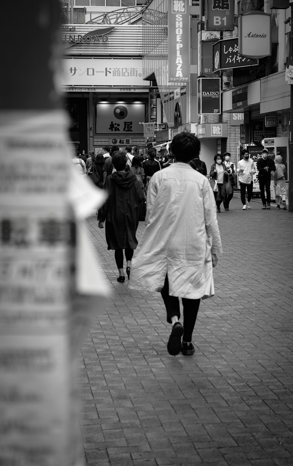 a black and white photo of people walking down a street