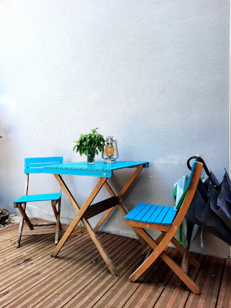 Sunlit outdoor bistro set with colorful folding chairs on a wooden deck.