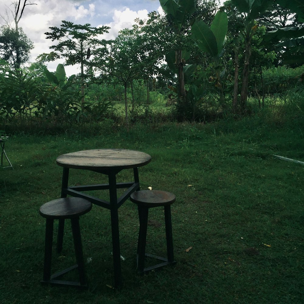 a table and two stools in the grass