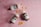 Three brown pill bottles with white caps, each labeled with green and white text, are scattered on a pink textured surface. Between the bottles, several small, round, yellow tablets are arranged in clusters.