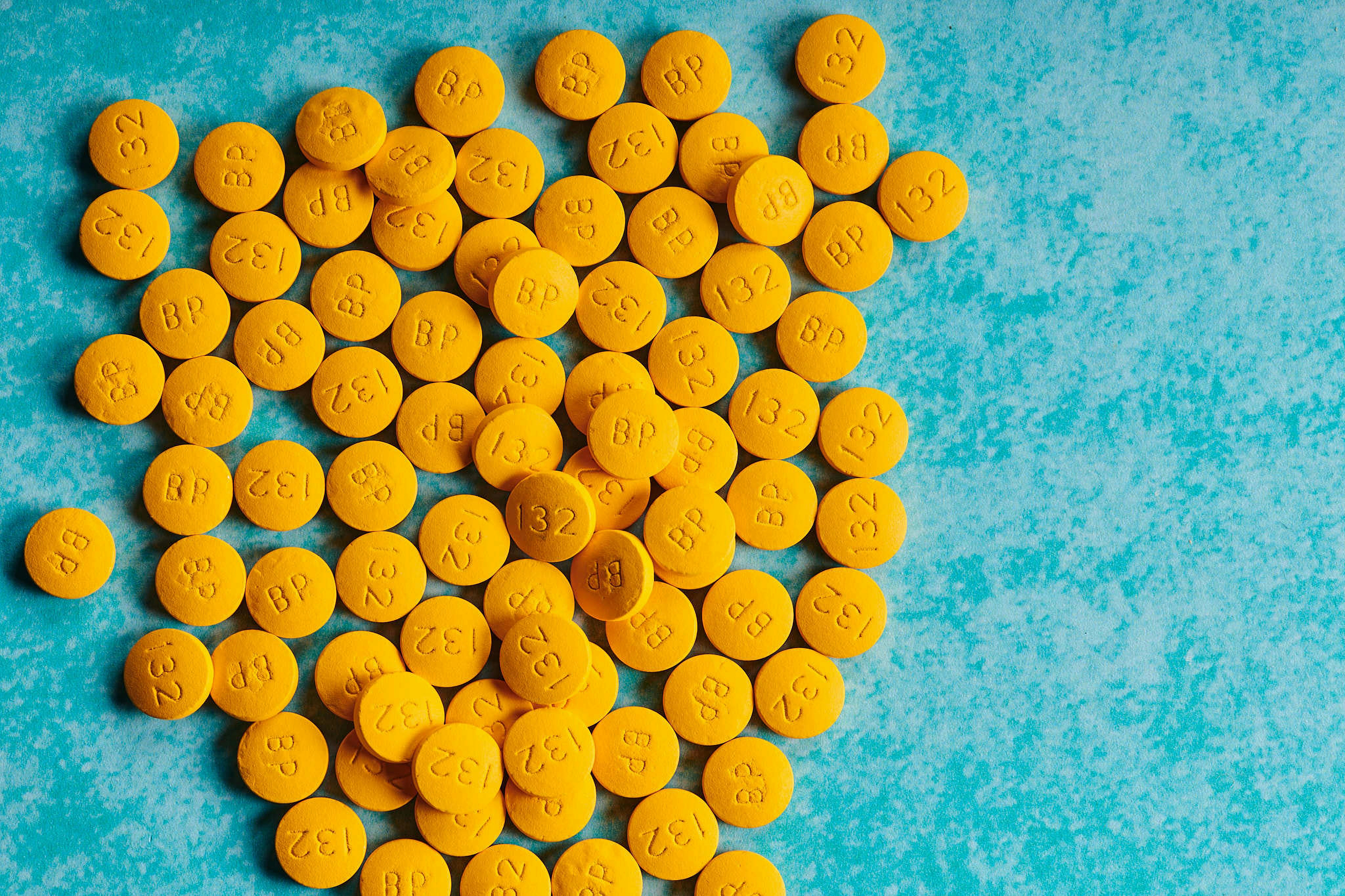 isolated pile of yellow medicine pills on blue background