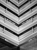 Angular architectural structure with repeating metallic patterns. The design features perforated metal sheets and linear elements, creating a modern and industrial aesthetic.
