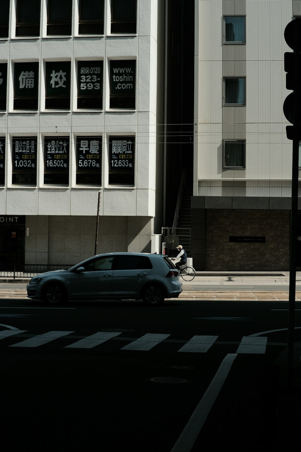 a car driving down a street next to a tall building