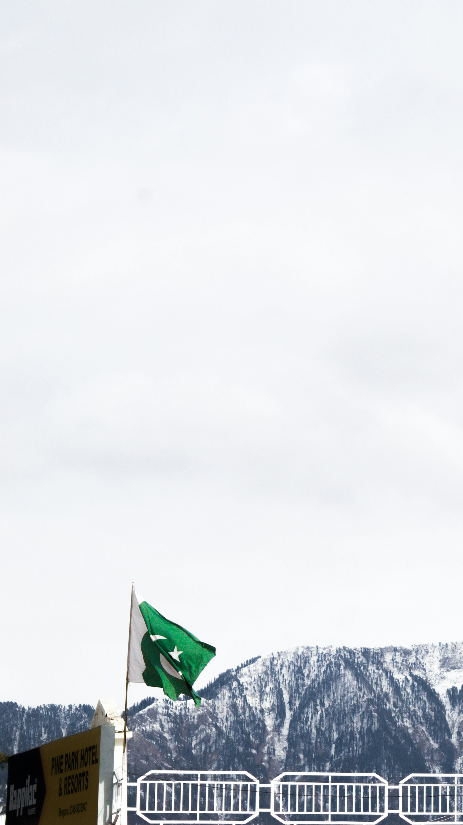 a green and white flag flying in front of a mountain