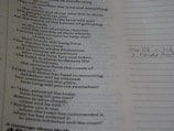 A page from a book is shown, with printed text on the left side. The text appears to be poetic or biblical in nature. To the right, there is a section with lined paper featuring handwritten notes, including a reference to a verse or page number.