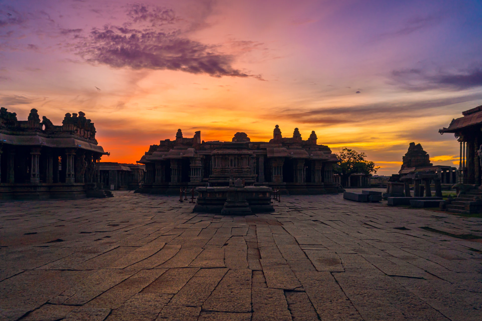A vibrant sunrise over the ancient temples of Tamil Nadu, with golden light casting long shadows on intricate stone carvings.