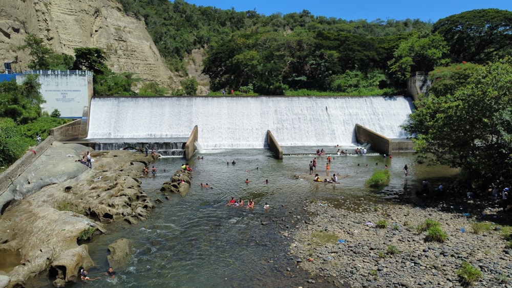 a group of people swimming in a river next to a dam