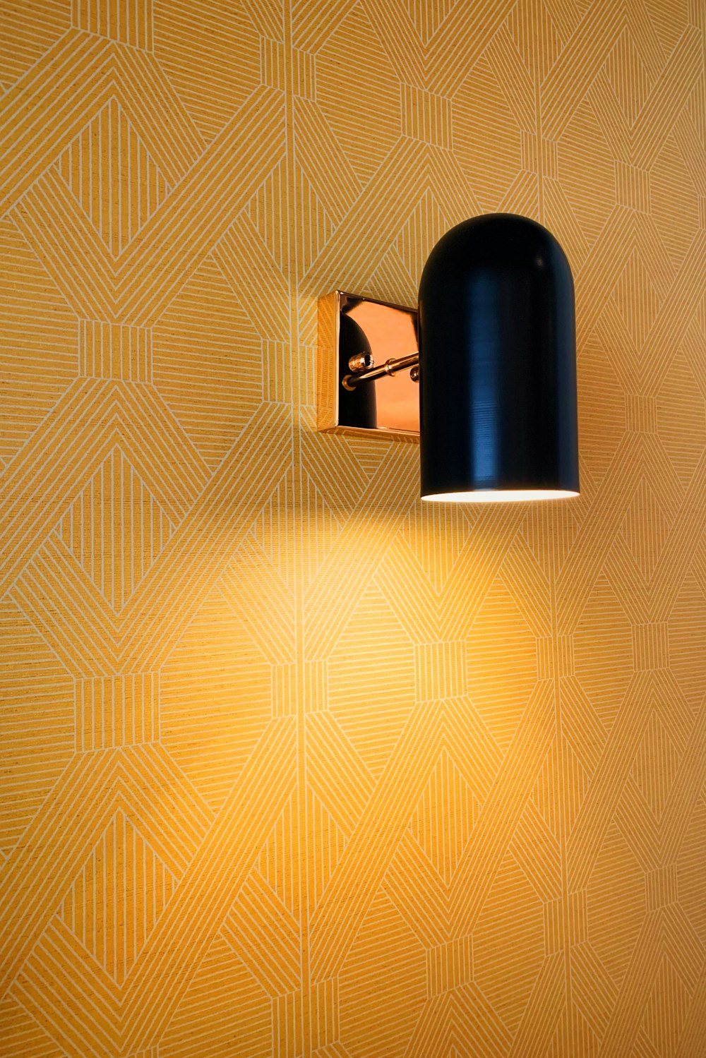 a black lamp on a wall next to a yellow wall