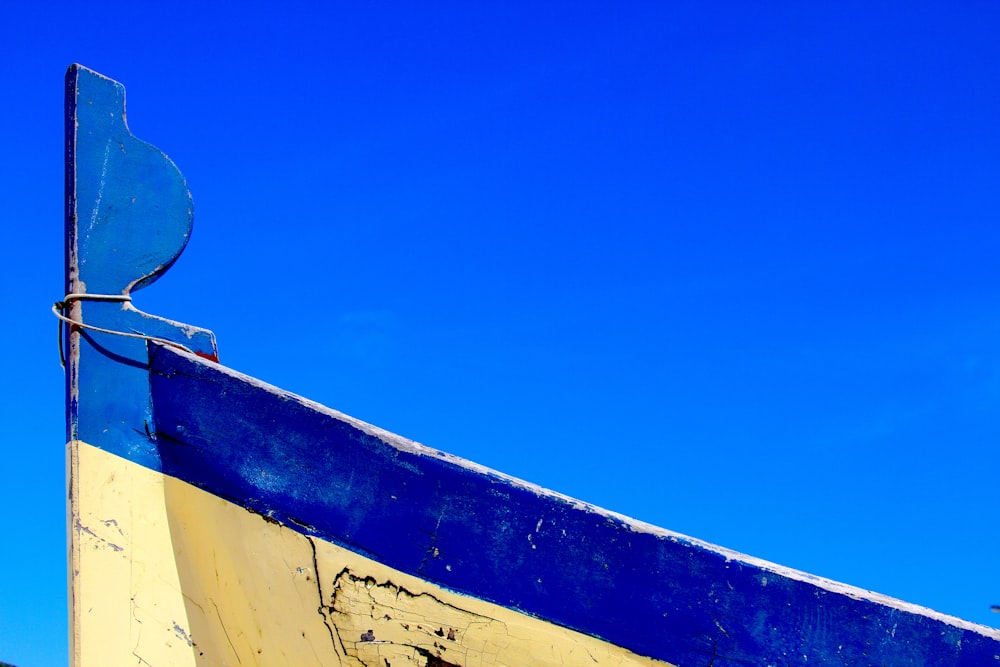 a blue and yellow boat with a blue sky in the background