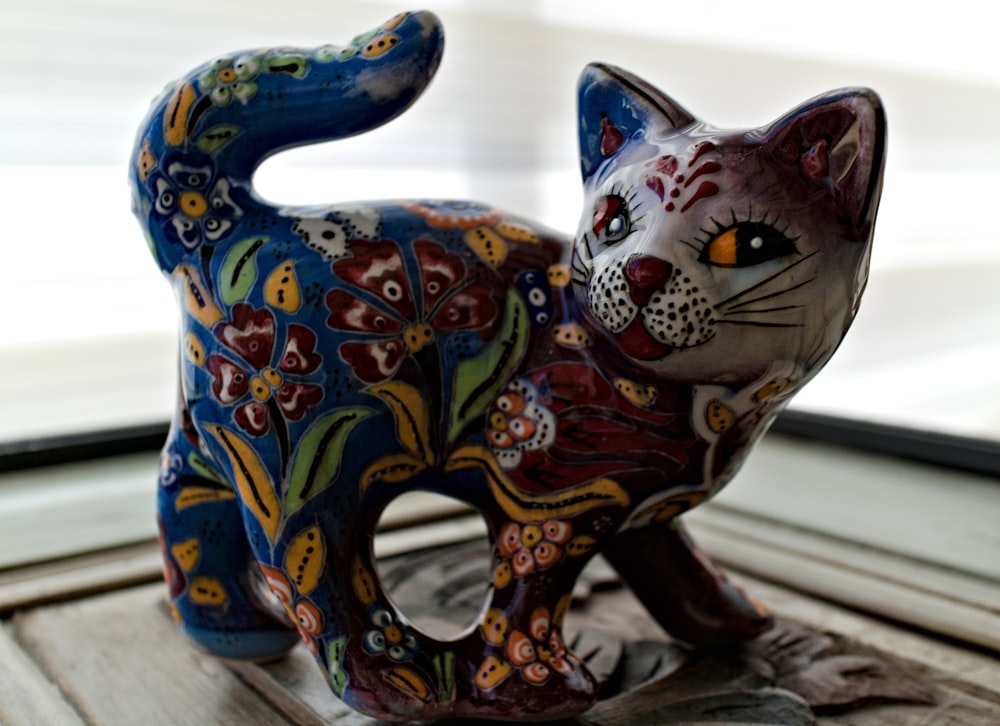 a colorful cat figurine sitting on top of a window sill