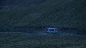 A comfortable and modern passenger shuttle bus driving on a scenic road during sunset.