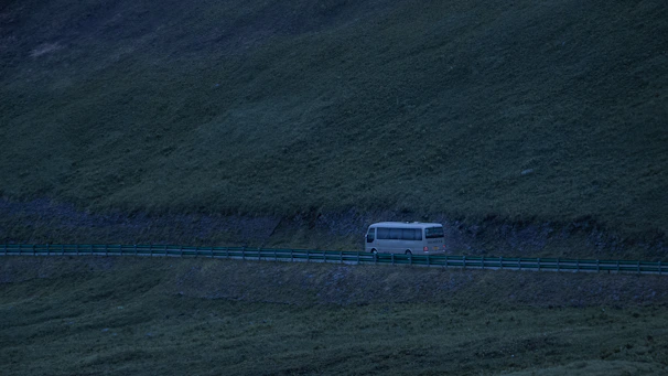 A modern bus traveling along a scenic highway at sunset.