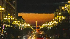 Street lamps lining a quiet city street glowing softly in the evening.