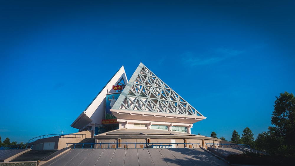 a large building with a triangular roof and a sky background