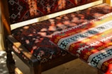 A beautifully woven battaniye draped over a rustic chair near a window.