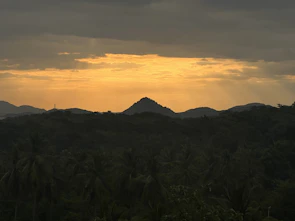 Sunset view over the Serra Malagueta mountains with lush greenery and dramatic skies.