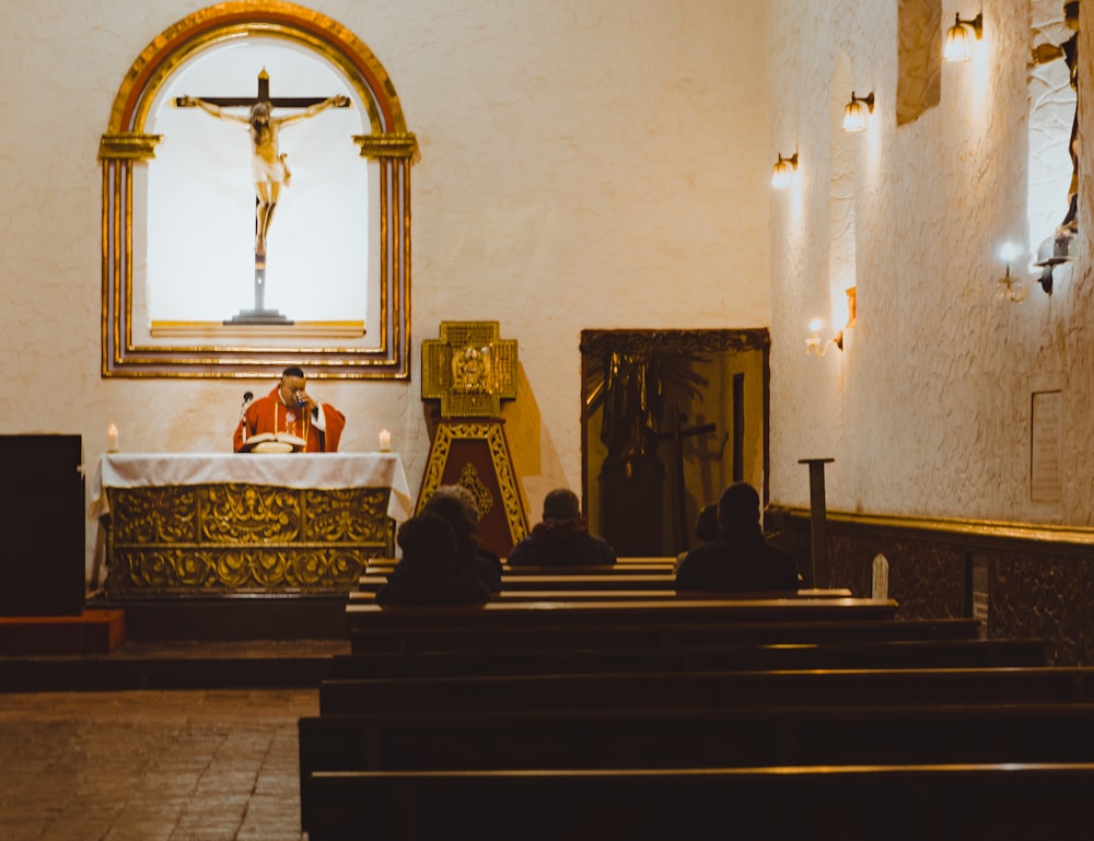 a man sitting in front of a cross in a church