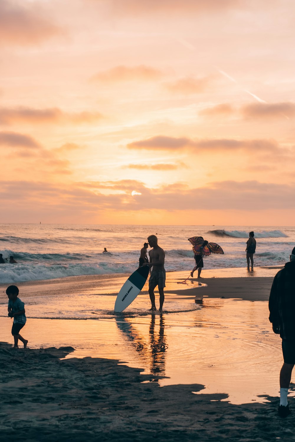 a group of people standing on top of a beach next to the ocean