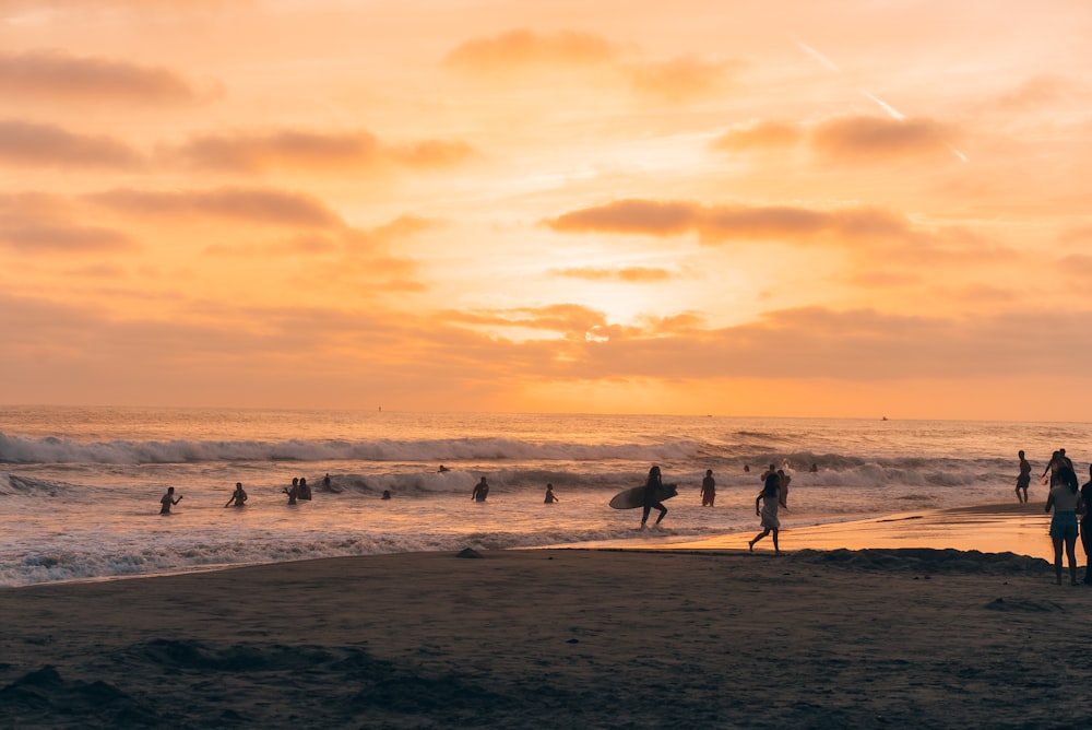 a group of people standing on top of a beach next to the ocean