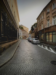 a cobblestone street lined with parked cars