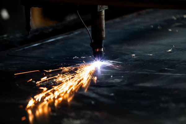 A modern CNC plasma cutting machine in action, slicing through metal with bright sparks flying.