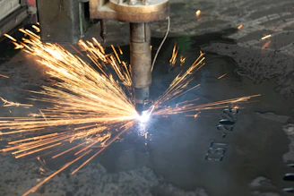 a welder cutting a piece of metal with sparks